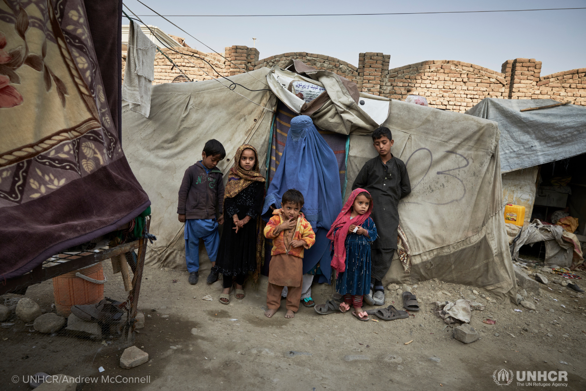 Afghan family standing outside shelter