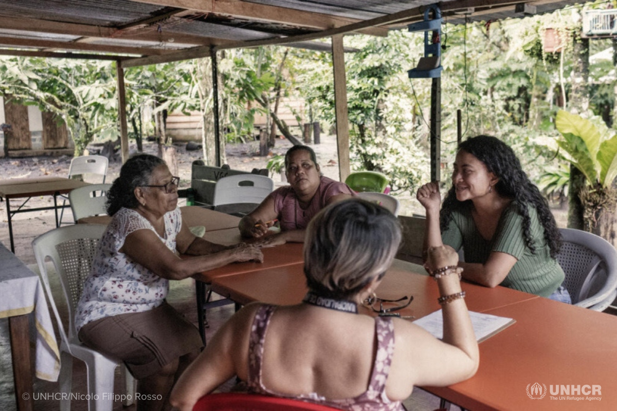 Vicenta (left, white blouse) and her collaborators Maricela Gutiérrez (center) and Dara Arguello (right) attend a meeting with a member of the local community at the farm. © UNHCR/Nicolo Filippo Rosso