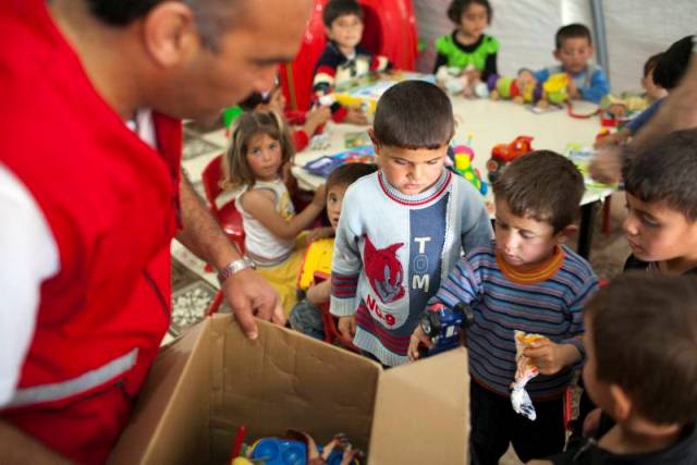 A group of excited and curious Syrian boys converge on a box full of goodies.