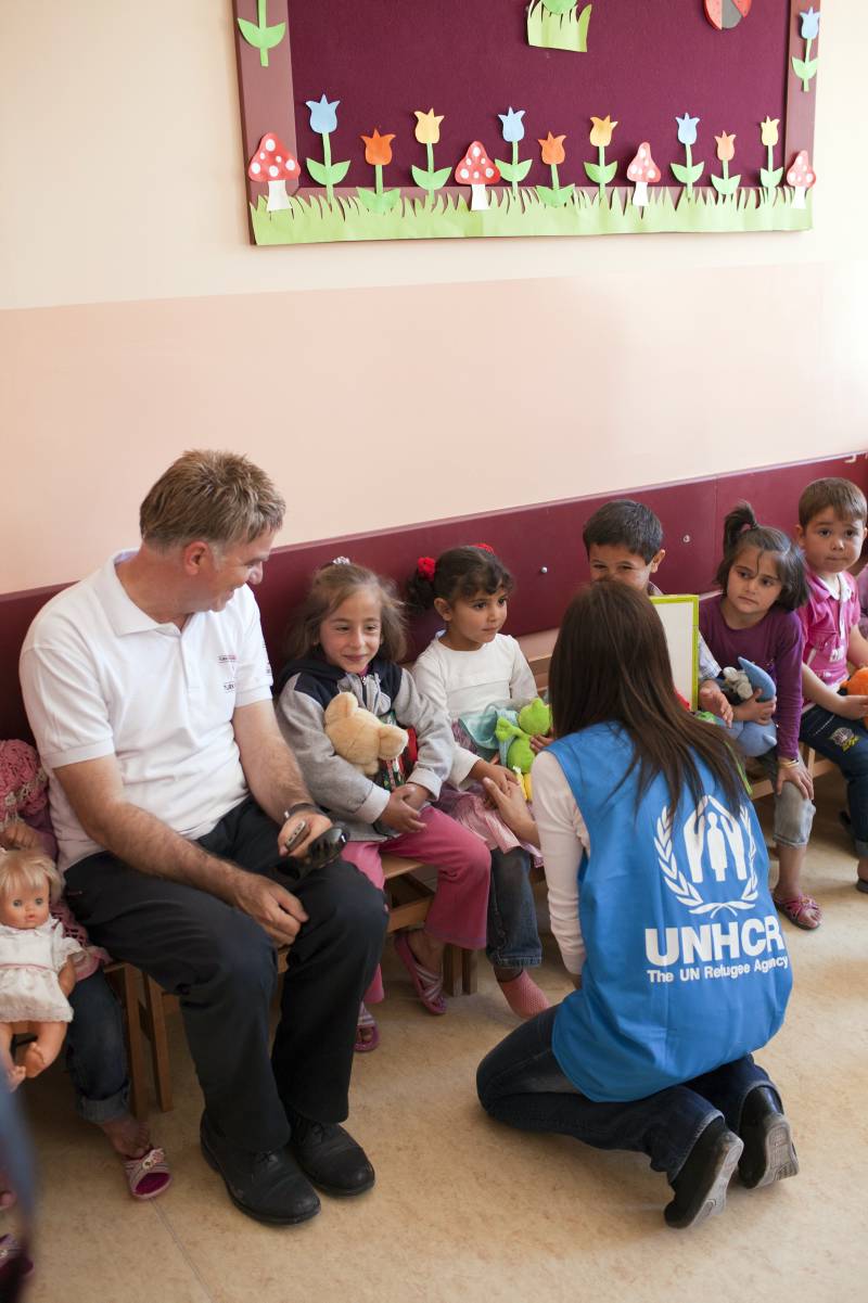  UNHCR staff member asks these children if they are happy with their new toys. The smiles give her their answer.
