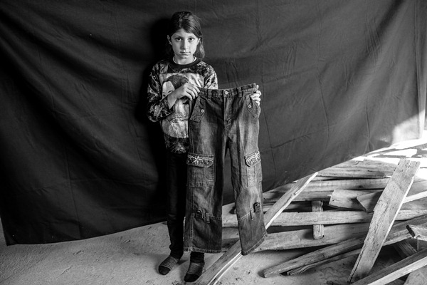Leila, 9, holds up a pair of jeans that she brought with her from Syria to Erbil in the Kurdistan Region of Iraq, where she and her family found shelter.