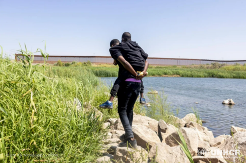A father from Haiti carries his son across the border between Mexico and the United States to seek asylum.
