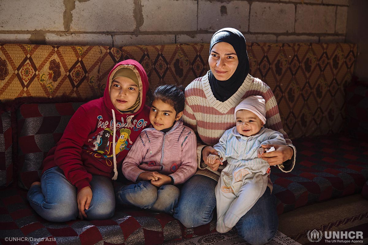 Syrian refugee Suzanne, 32, holding her daughter Mona, 6 months, sits alongside her older daughters Jana, 6, and Roua, 10, in the substandard building where the live in the Bekaa Valley, Lebanon. They share the small cramped space with Suzanne’s mother, older sister and brother-in-law.