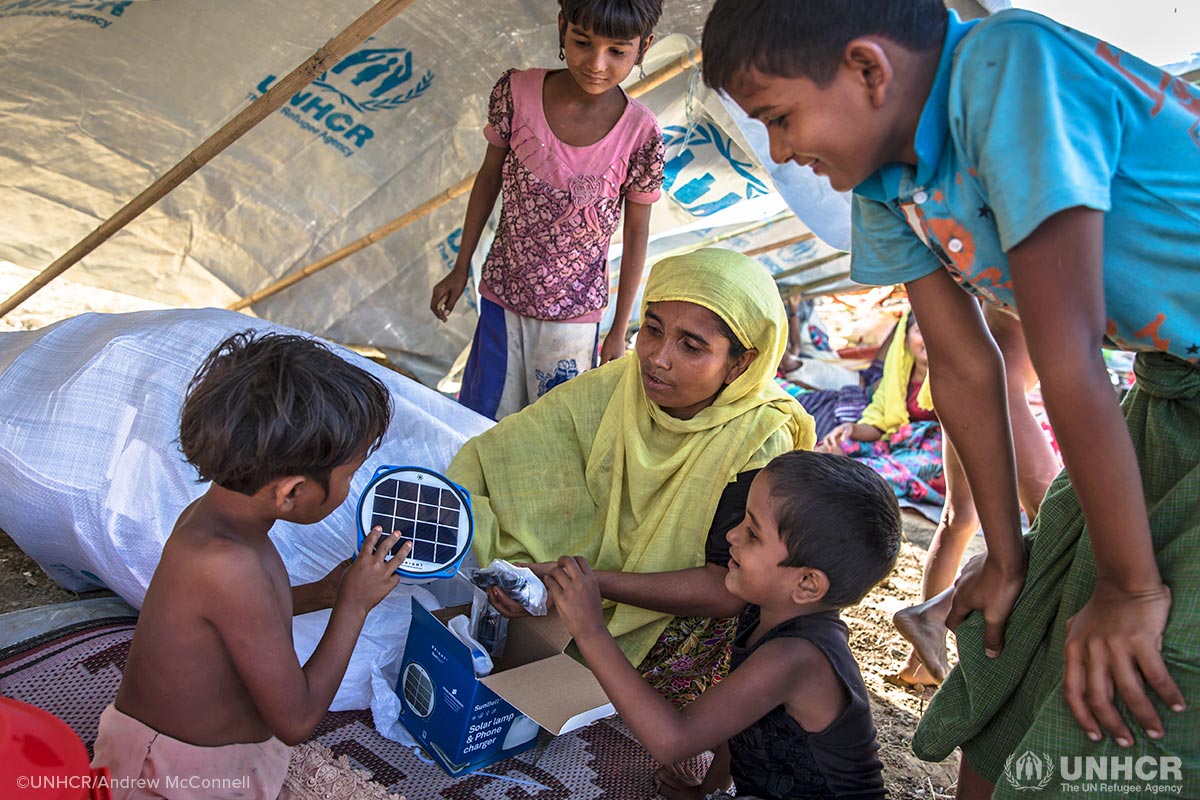 Rohingya mother Laila Begum, 30, and her children (from left) Aysha, 7, Rogida, 12, Kishmot Ara, 5, and Mohammed Riaz, 13, receive their UNHCR Non-Food Items emergency relief pack in their makeshift shelter