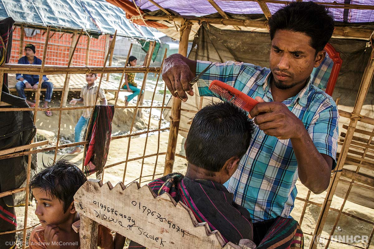 Hairdresser Najibullah, 28, cuts a customer's hair at his barber's shop in Moynerghona refugee camp, Bangladesh. Najibullah was a barber in Myanmar and borrowed some money from a neighbour in the camp to open his shop.