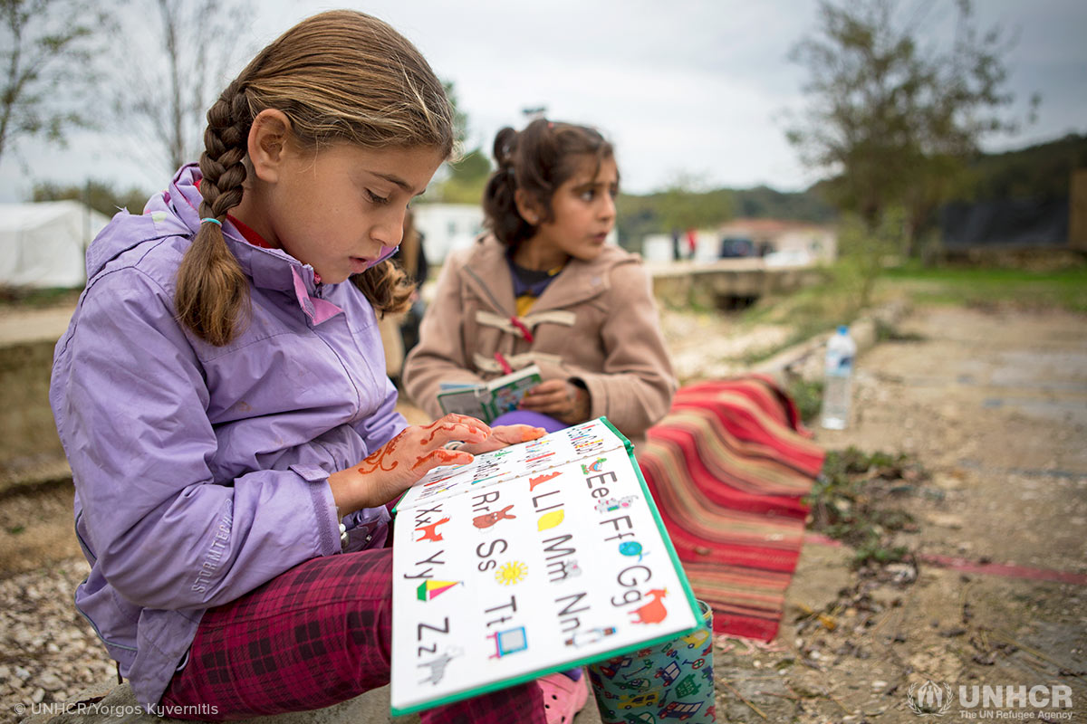 Two sisters from Syria, Zeinab (left), 7, and Elaf, 8, read books outside the newly built library at Filipadia camp on the Greek mainland.