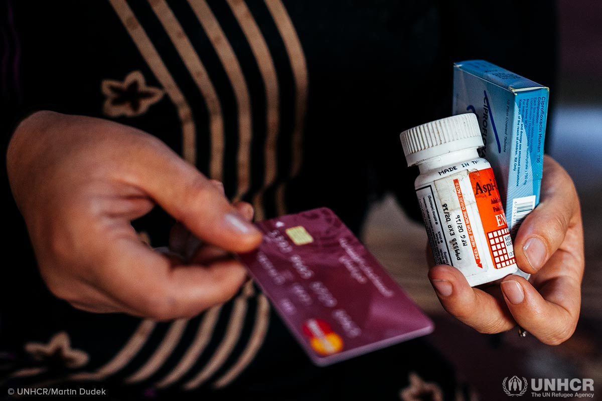 Nouf, 29, a mother of five from Homs, holds her children’s medicine and the ATM card she used to buy them thanks to the cash assistance of $175 she receives monthly from UNHCR.