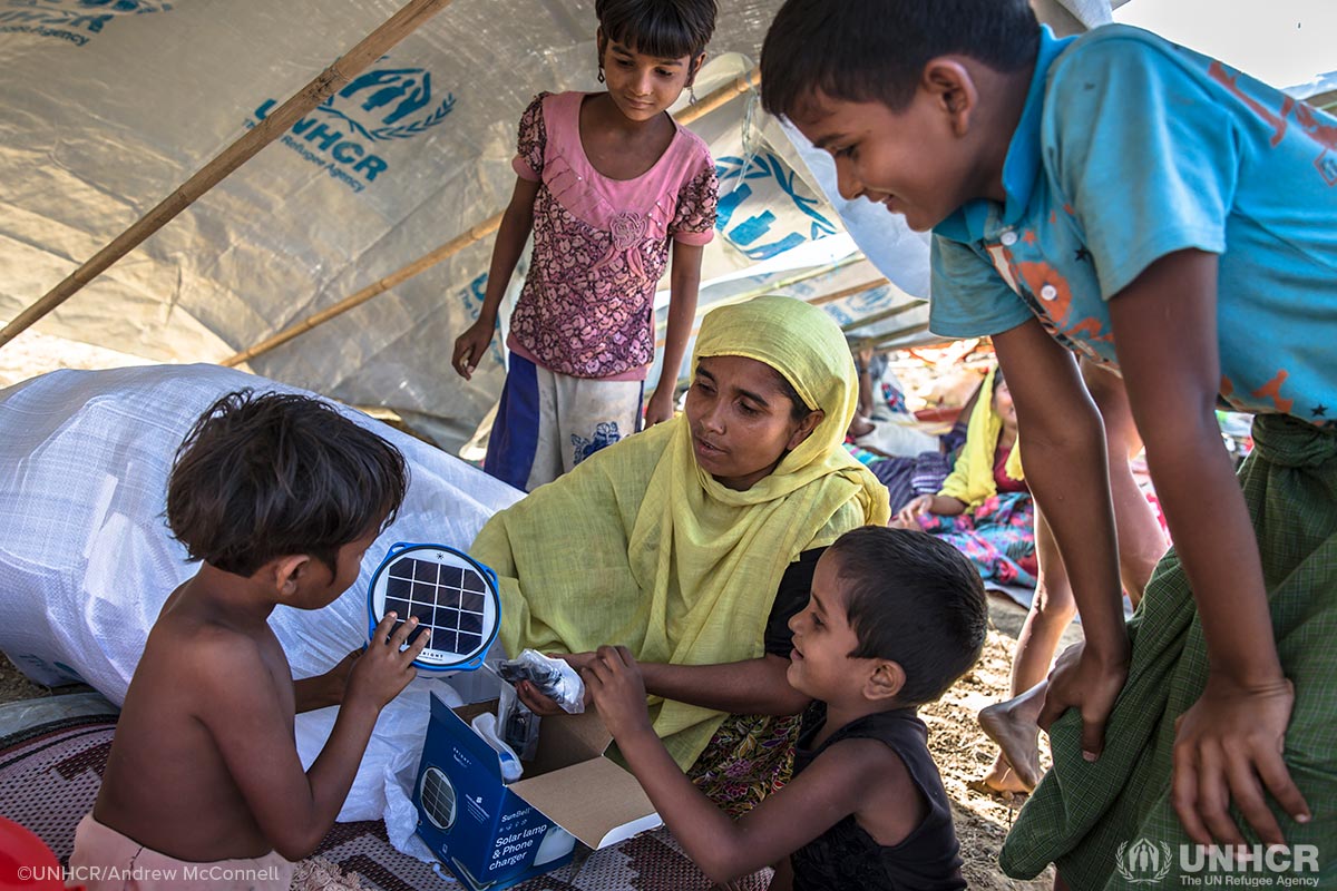 Rohingya mother Laila Begum, 30, and her children (from left) Aysha, 7, Rogida, 12, Kishmot Ara, 5, and Mohammed Riaz, 13, receive their UNHCR Items emergency relief pack in their makeshift shelter at Kutupalong refugee camp, Bangladesh. The pack includes a solar lantern, phone charger, blankets, tarp and kitchen set.