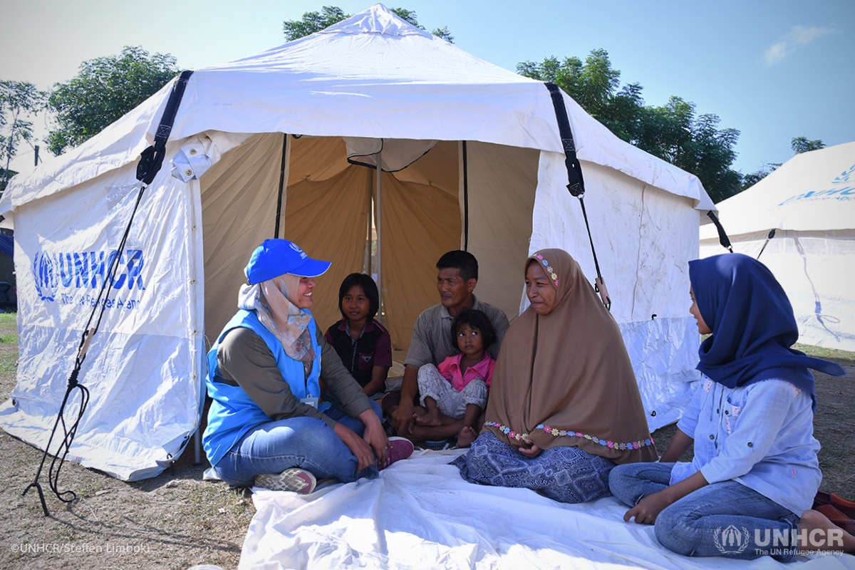 A UNHCR staff member talks to an internally displaced family, including father Bampek, 45, his wife Vemy, 41, and their daughters (from left) Almaida, 12, Nelfi, 4, and Vita, 16, outside a family tent.