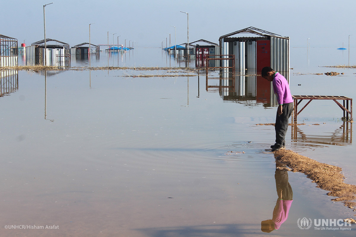 A displaced young boy sees his reflection in the rising water at Al-Areesha camp.
