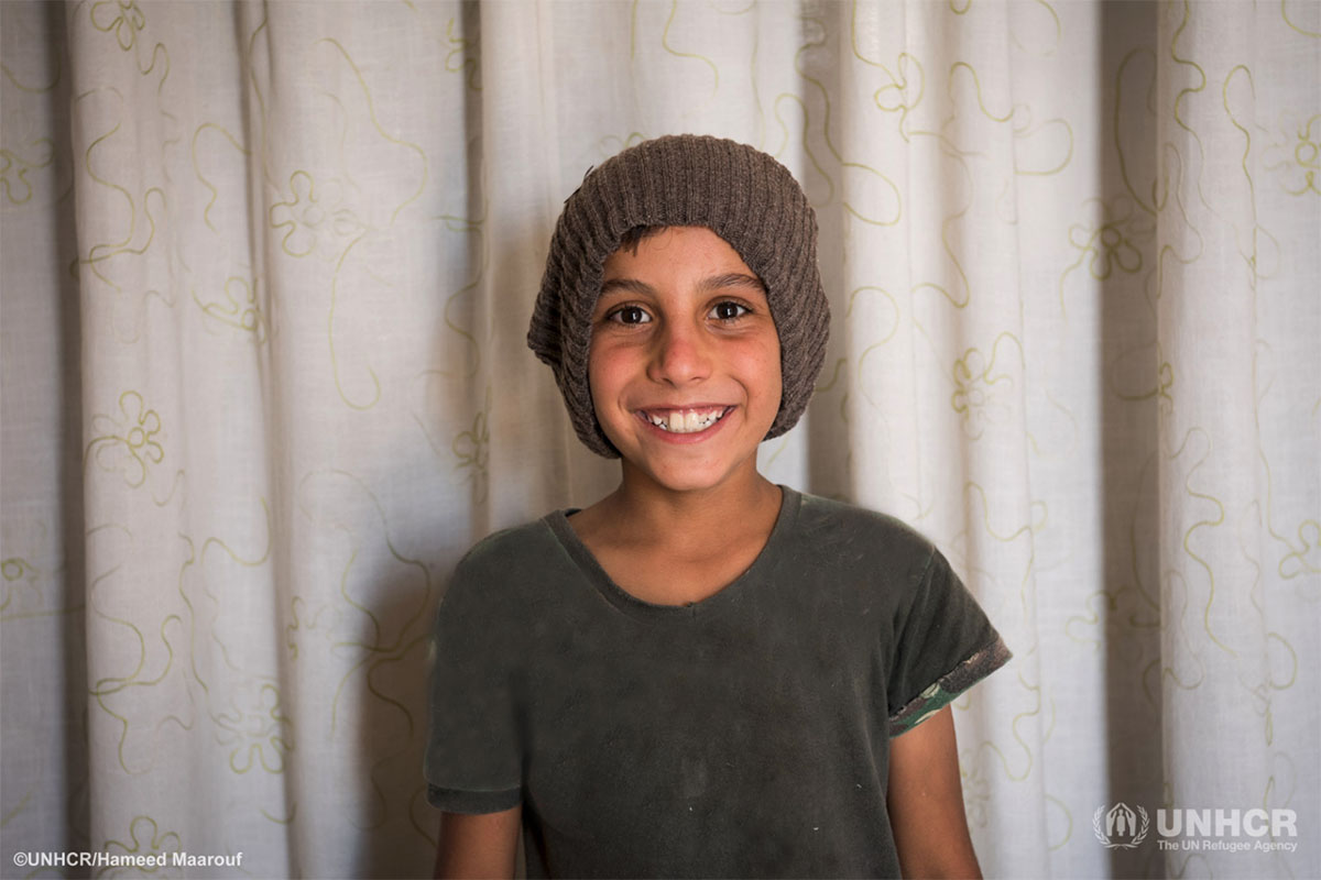 8-year-old Syrian refugee Moayyed wears a new warm hat from the UNHCR winter clothing kit.