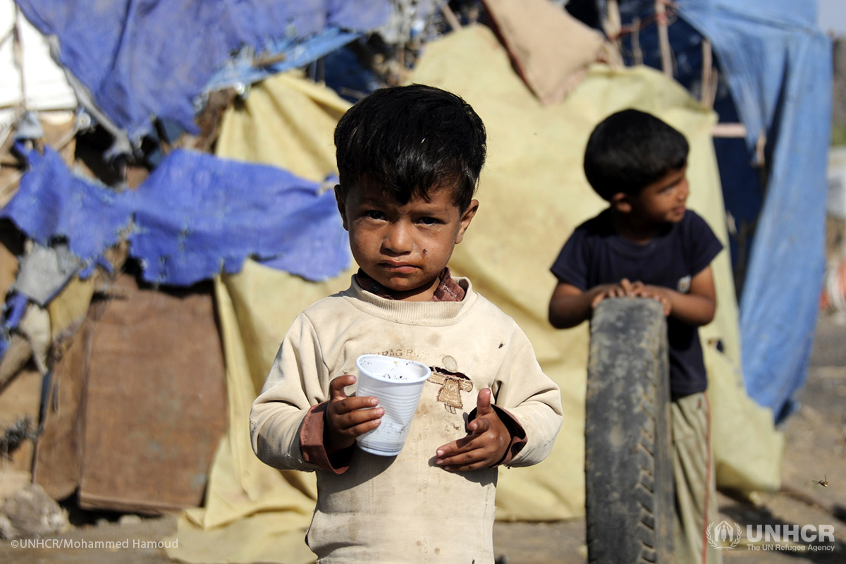 A boy stands outside his family’s makeshift shelter at the Dharawan settlement in Yemen.