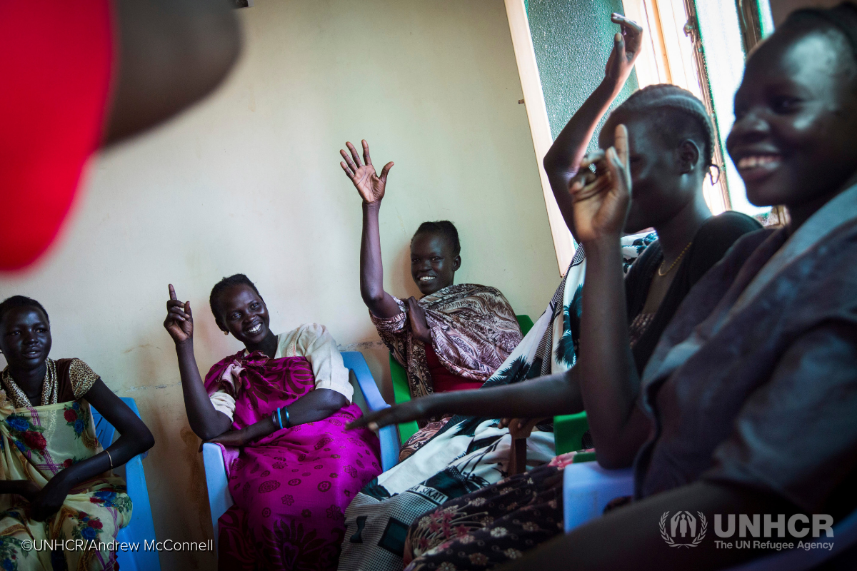 South Sudanese women in a classroom raise their hands