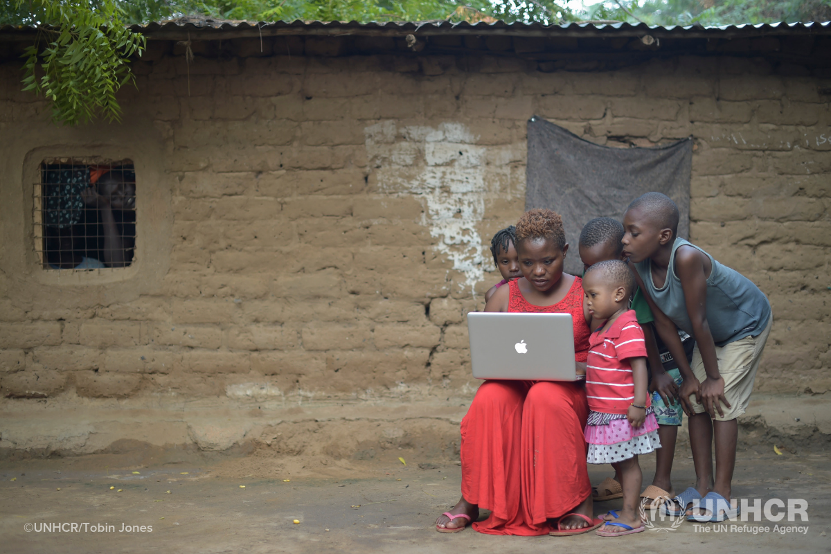Refugee family on computer outside shelter