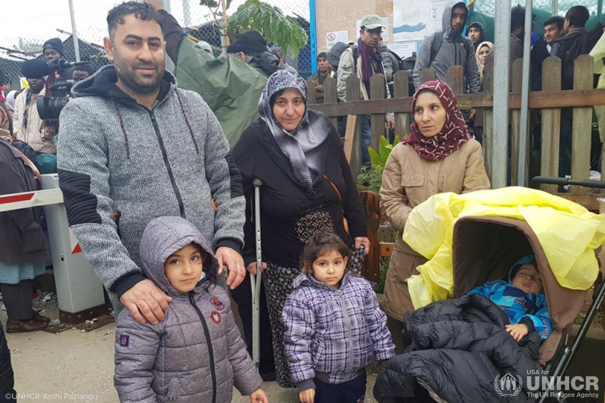 refugee family of one man two women and three children looking at camera