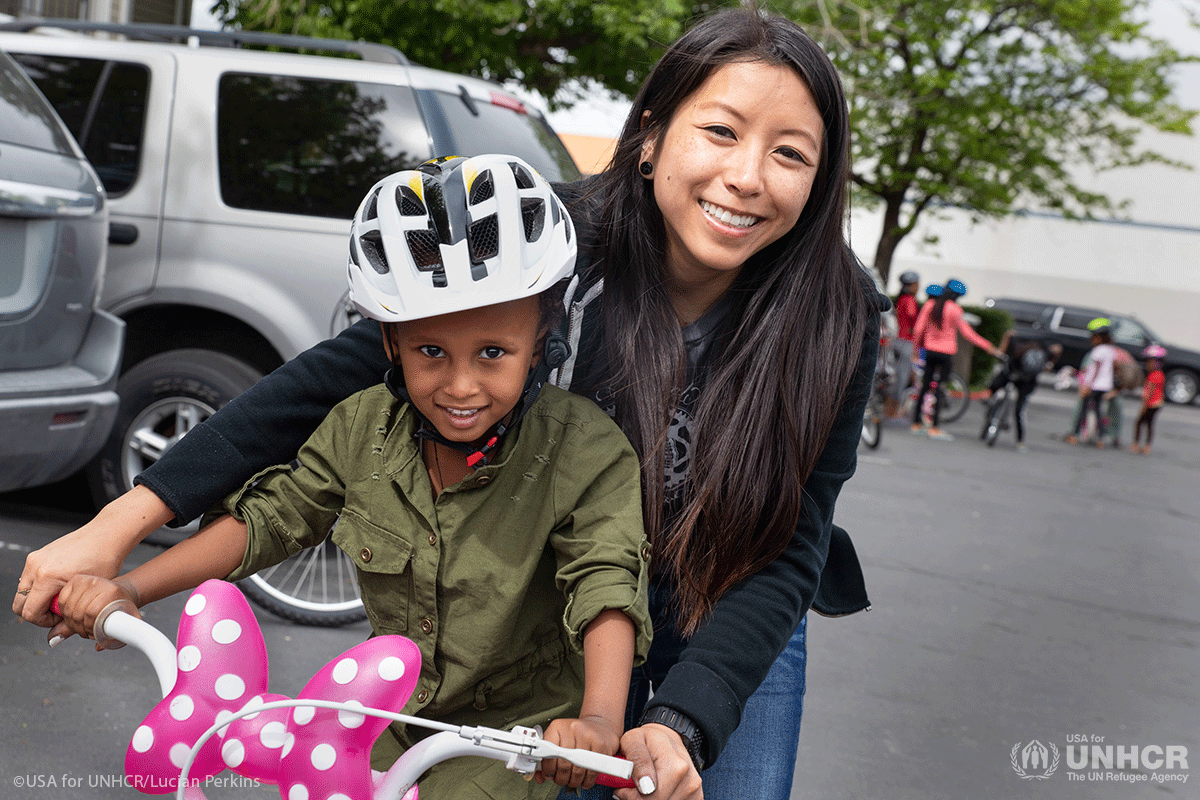 Amy Ngyuen Wiscombe helps a child onto a bike
