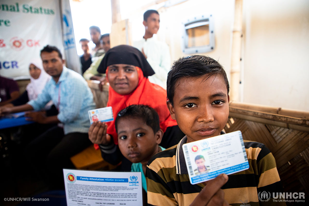 A Rohingya refugee family from Myanmar show their new identity documents after completing a UNHCR run registration process.