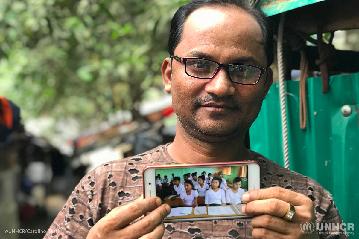 Rohingya refugee Nur Alam shows a photo of his pupils at a school in Maungdaw, Myanmar where he was once headteacher.