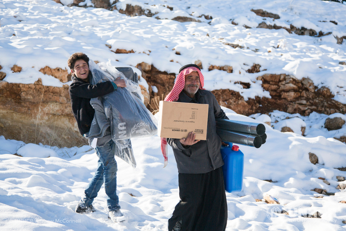 Syrian refugees carrying winter supplies, winter survival kit