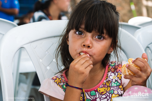 Talia, a 4-year old girl who fled her home in Venezuela with her family, eats an orange.
