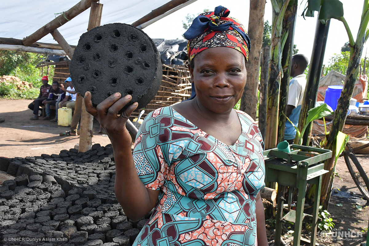 saverina holds up a brick she made from recycled materials