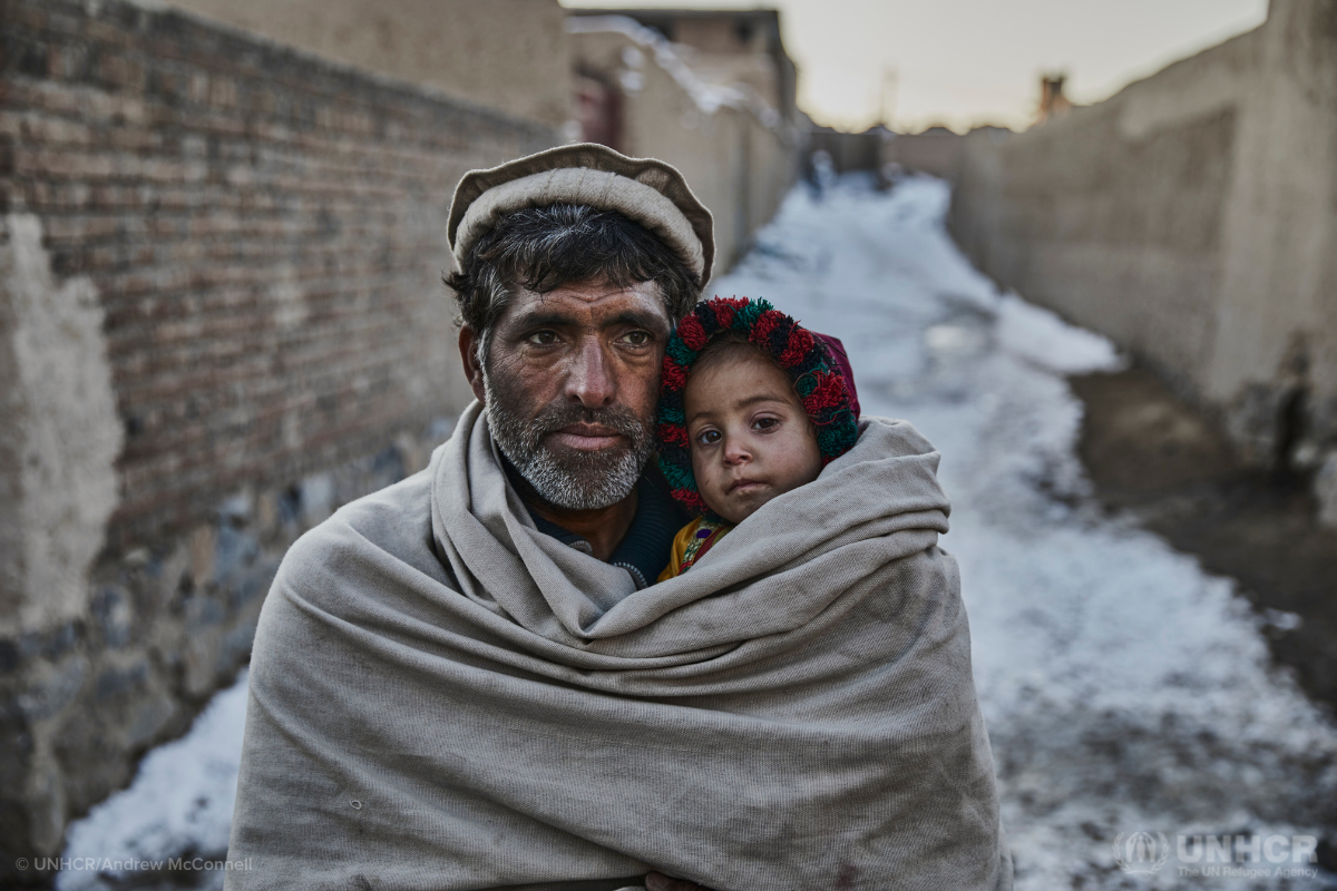 Internally displaced Afghan father holds his two-year-old daughter close to keep her warm
