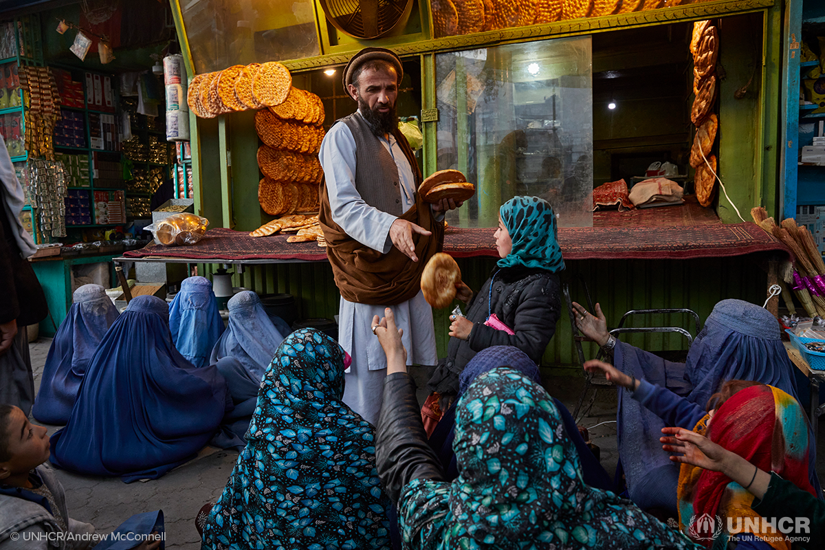 Afghani man handing out bread to children and women