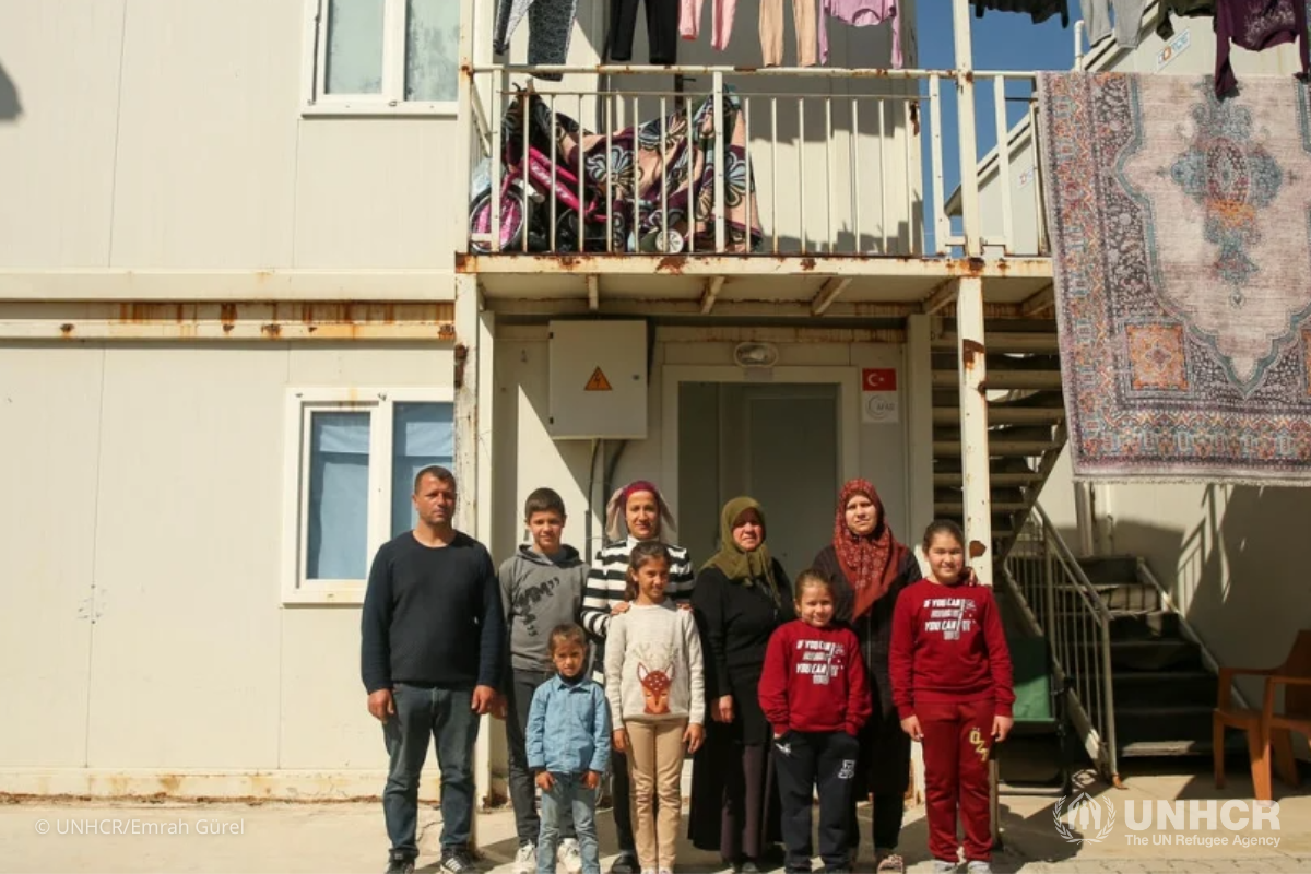 The Erkan family stand outside their shelters at the Boynuyoğun Temporary Accommodation Centre (TAC) in Hatay, Türkiye.