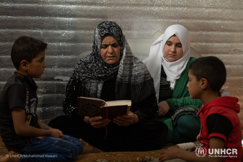 Um Hadi reads the Qur’an with her three children Hadi (8), Osama (7) and Shatha (13) at home in Azraq Camp.