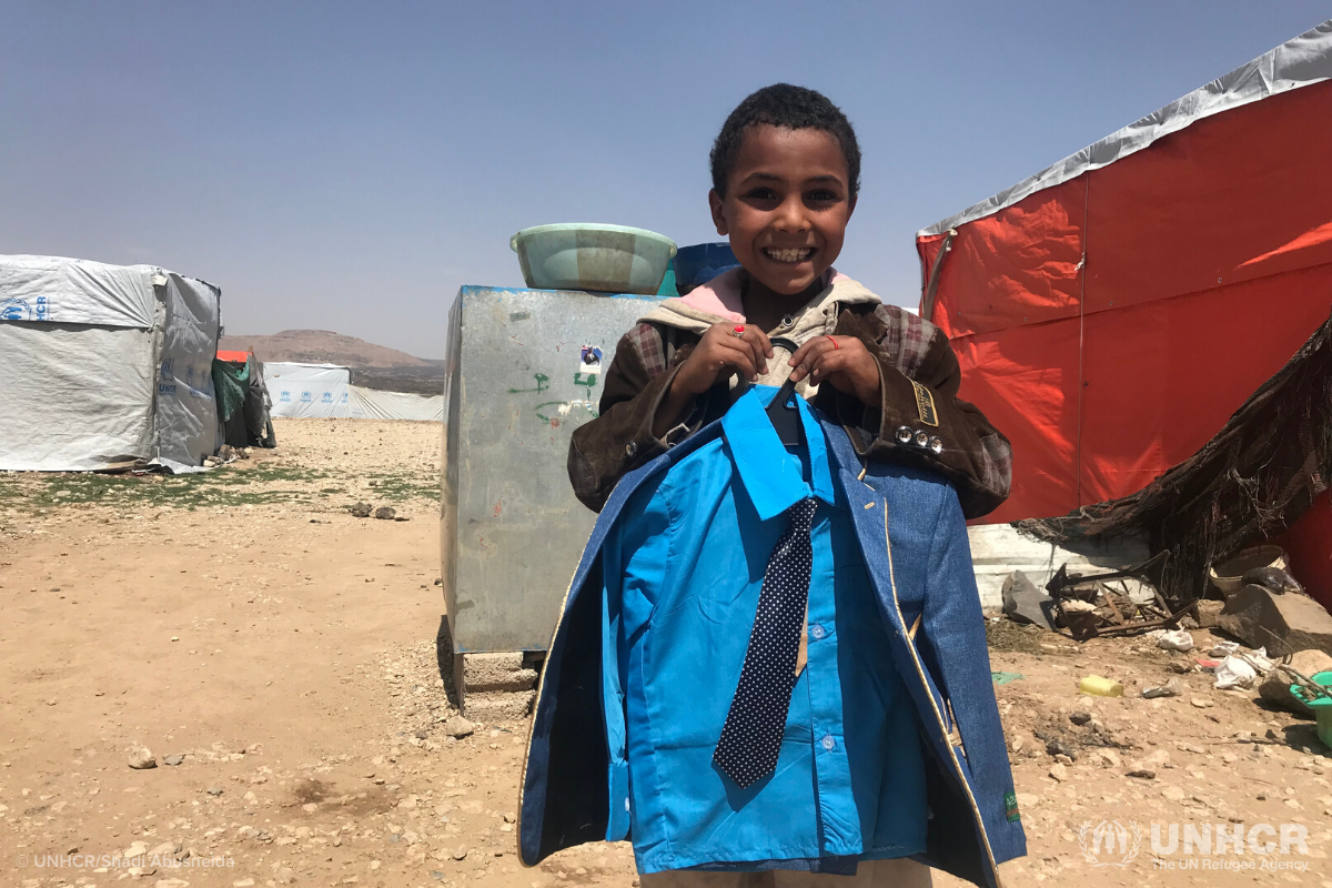 Ghareeb holds his new clothes and smiles