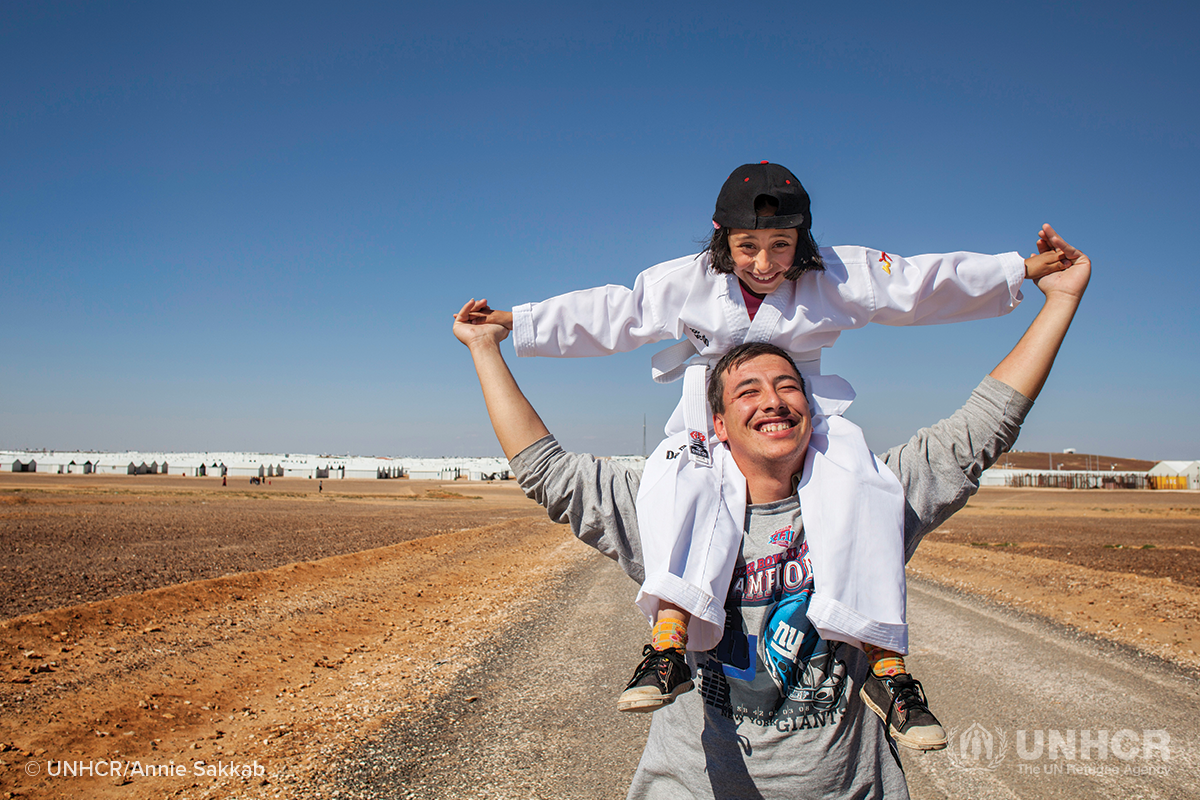 syrian refugee sister sits on her brothers shoulders
