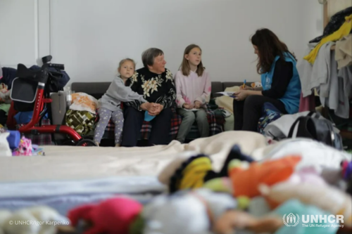 Lyudmyla, 87, and her granddaughters Sasha and Lera are helped by UNHCR staff at a reception centre in Uzhhorod, western Ukraine.
