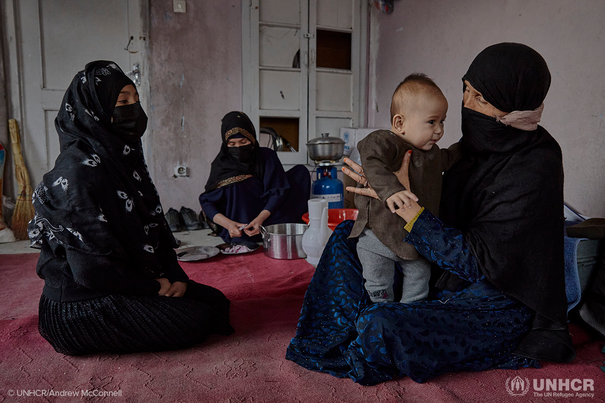 Sakina holds her grandson while speaking to her daughter