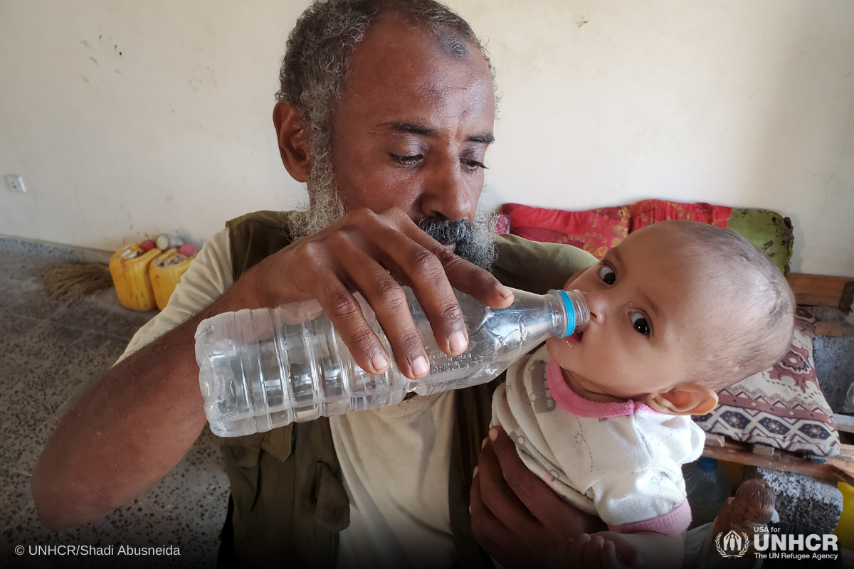 Sameer gives water to his boy inside a collective center for displaced people in Hudaydah, Yemen