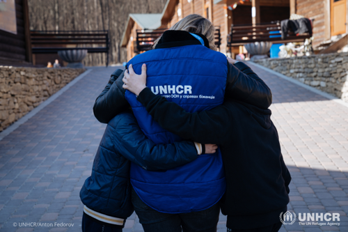 UNHCR staff members hugs two boys who fled Ukraine.