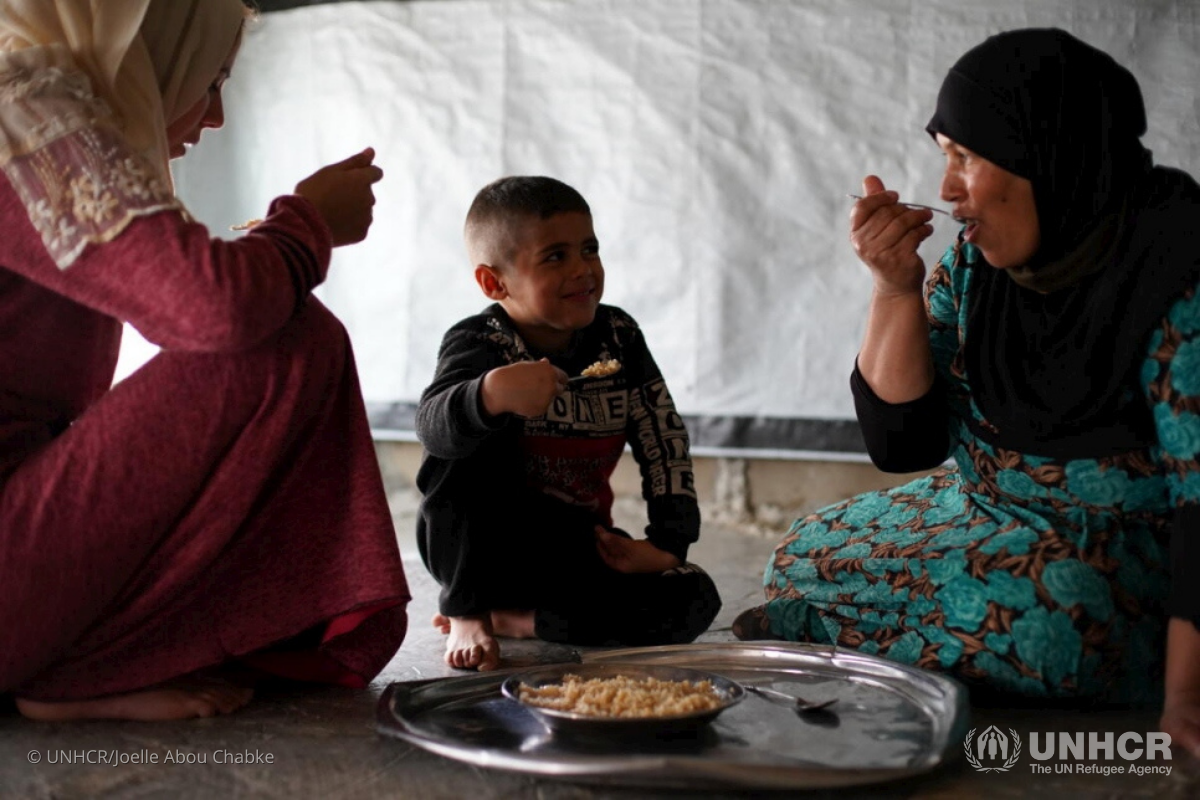 Khadra shares a meal with her daughter-in-law and nephew inside the one-room tent that shelters her and nine other family members. 