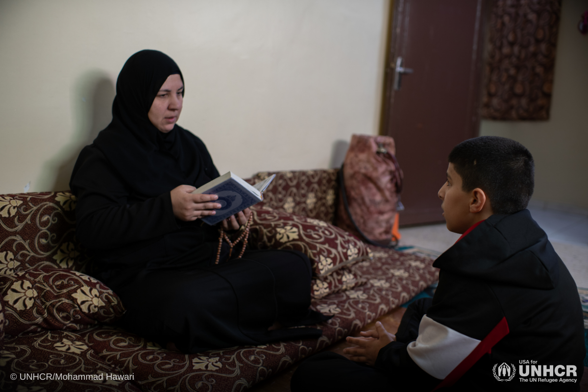 Jameela, a Syrian refugee living in Jordan, reads the Qur’an with her son Ali, 12, at home in Amman.